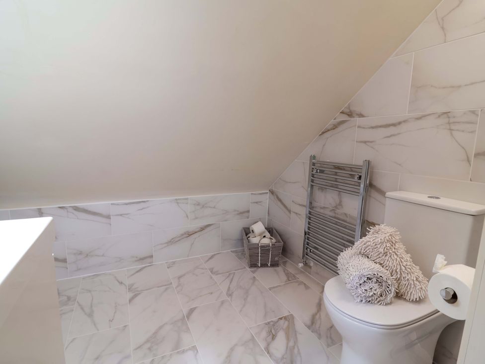 A bathroom with a toilet and towel rail at Honeysuckle Farmhouse in Tarporley