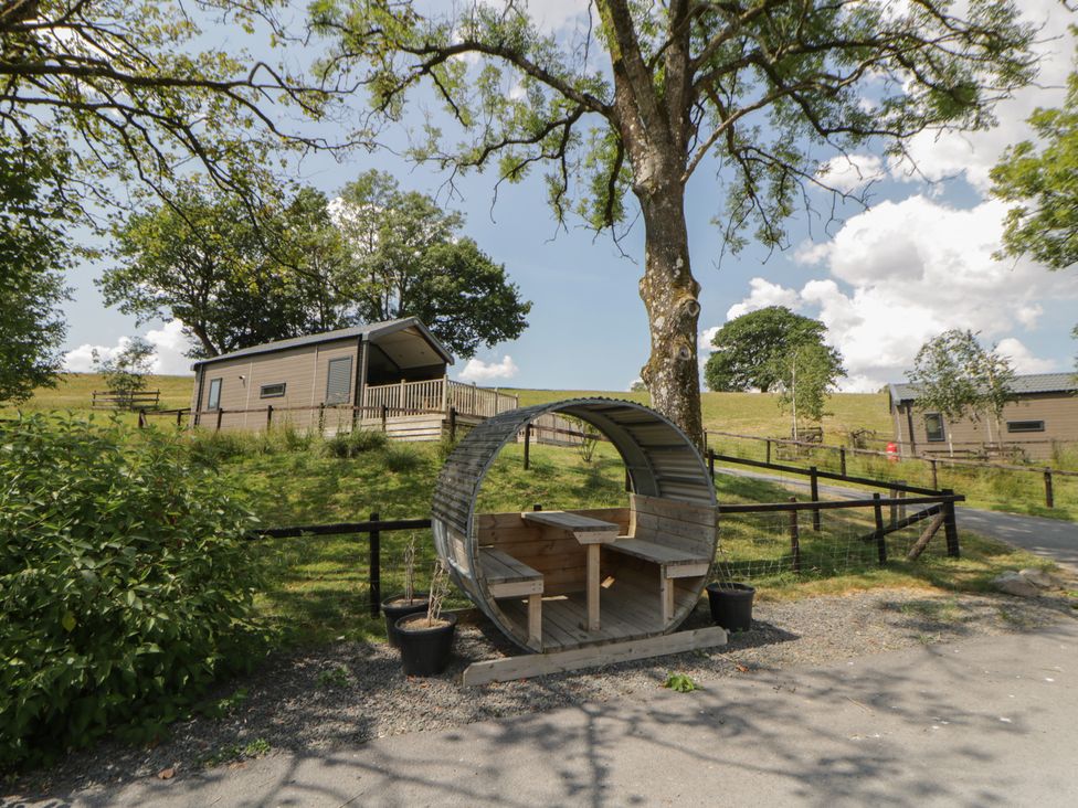 An outdoor area with a lodge and a circular bench at Meadow Retreat Nantmel near Rhayader