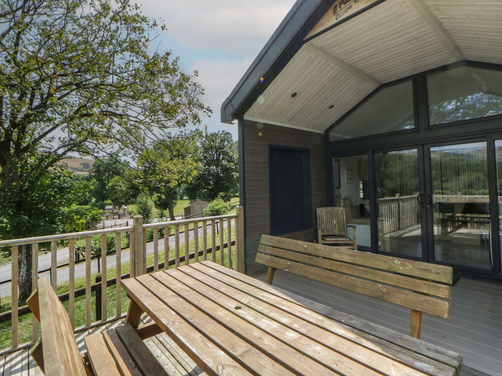 An outdoor area with wooden furniture and view of trees and road at Meadow Retreat in Nantmel near Rhayader