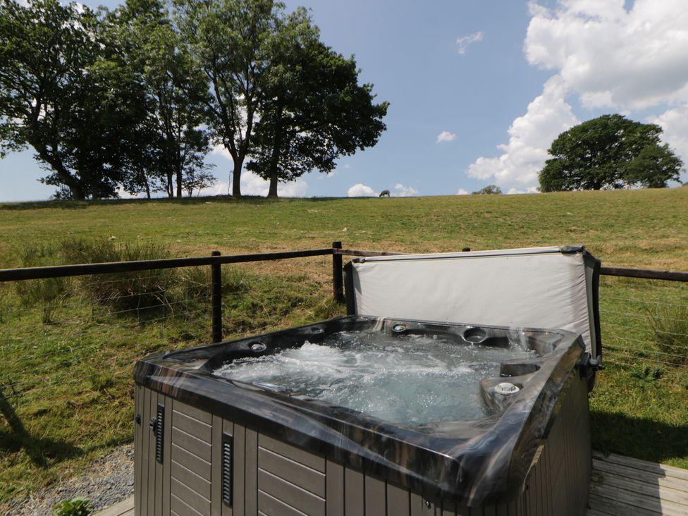 A hot tub with trees in the background at Meadow Retreat in Nantmel near Rhayader