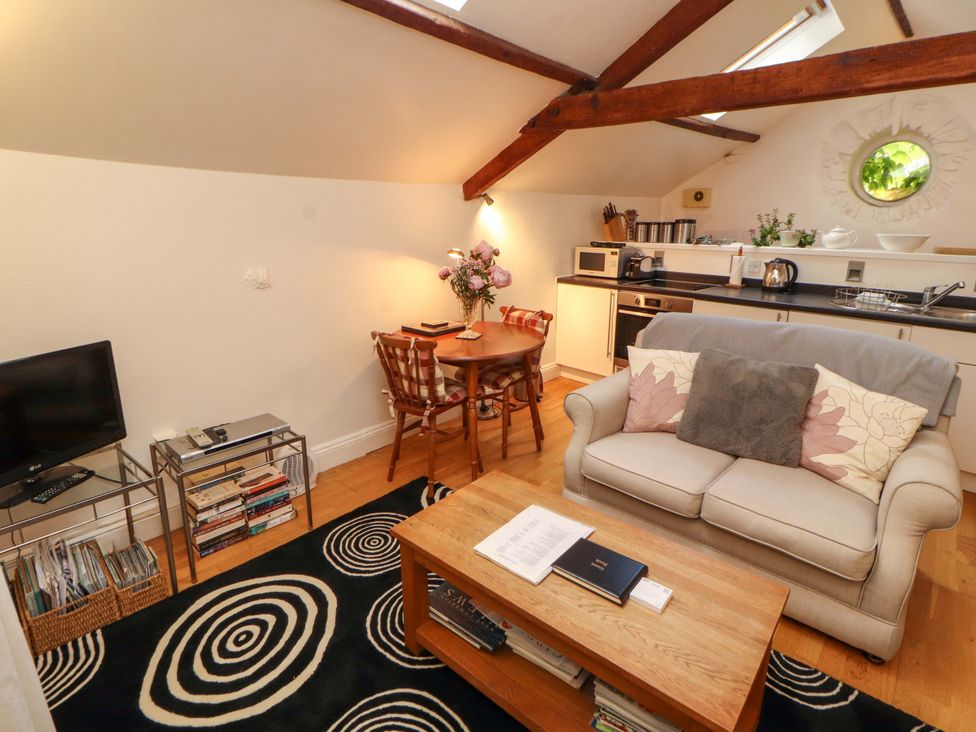 A living room with a sofa and dining area at Holemire Barn Lorton
