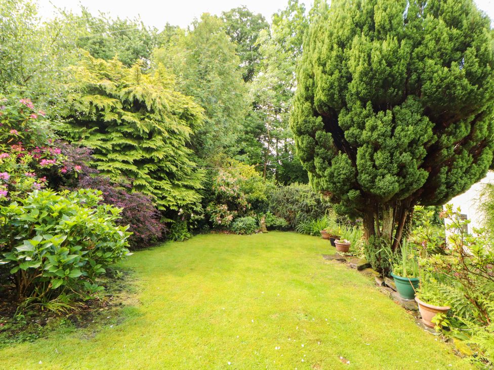 A garden with grass, trees, and flower bushes at Holemire Barn in Lorton