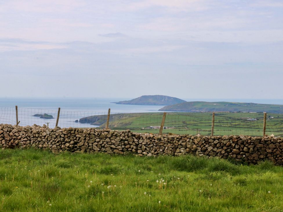 A view of a landscape with a stone wall and sea in the background at Dalar Deg Aberdaron