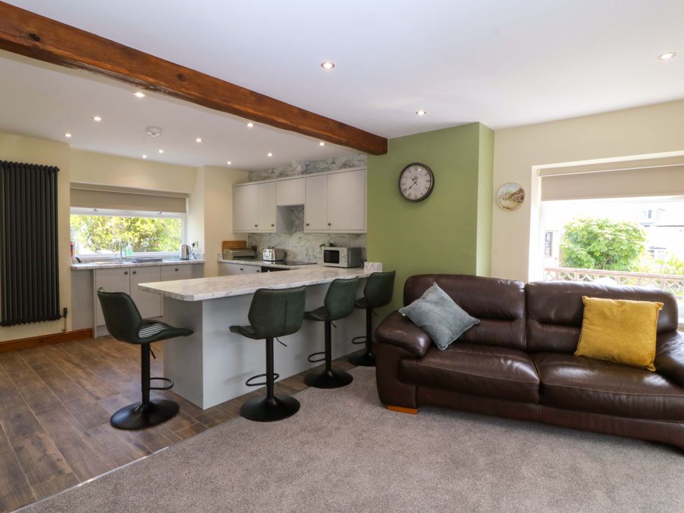 A kitchen with bar stools and a sofa at Dalar Deg in Aberdaron