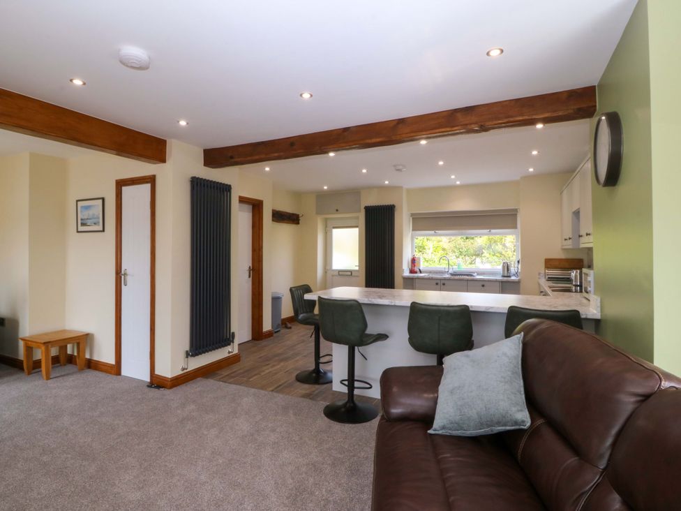 A living room with a kitchen counter and bar stools at Dalar Deg in Aberdaron
