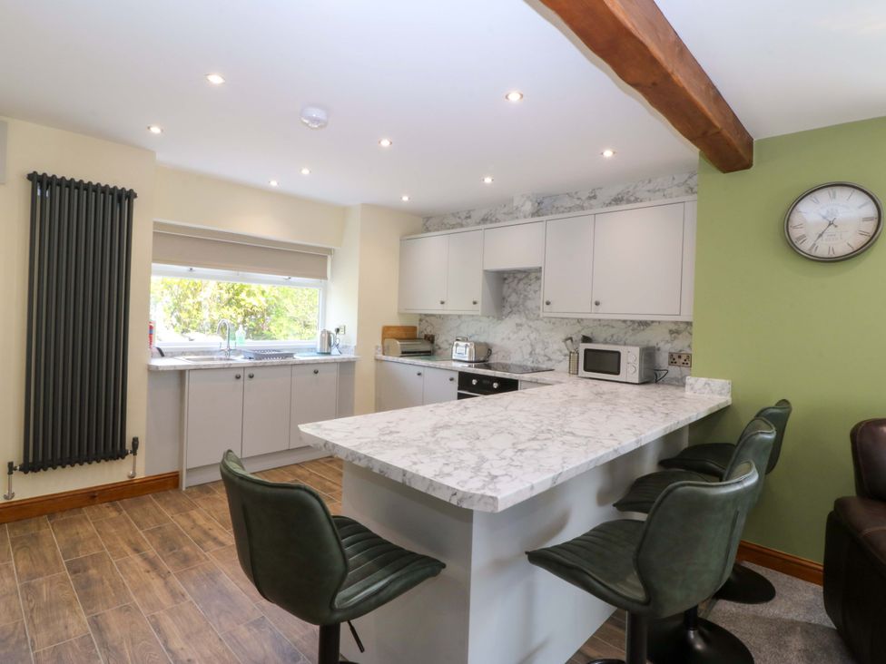 A kitchen with a sink and bar stools at Dalar Deg in Aberdaron