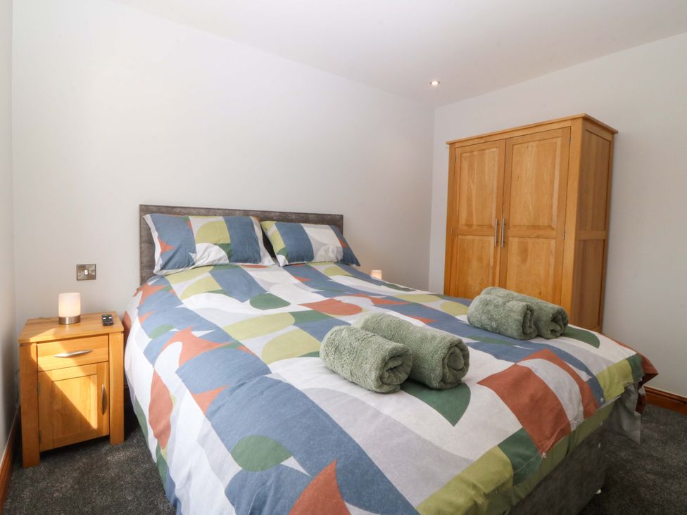 A bedroom with a bed and nightstand at Dalar Deg in Aberdaron