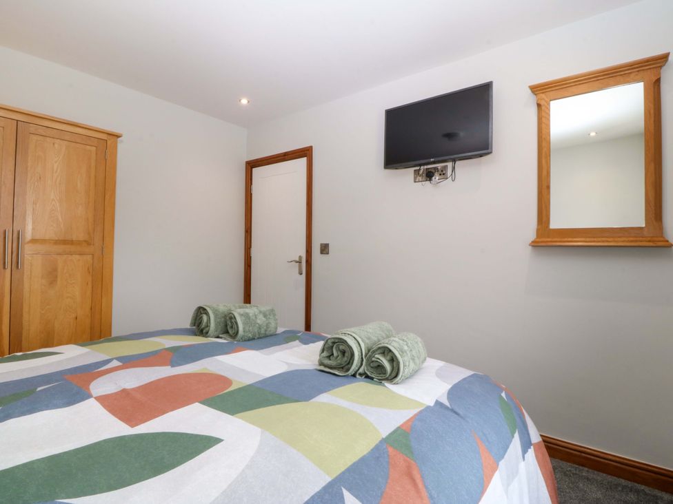 A bedroom with a bed, towels, wardrobe, and a tv at Dalar Deg in Aberdaron