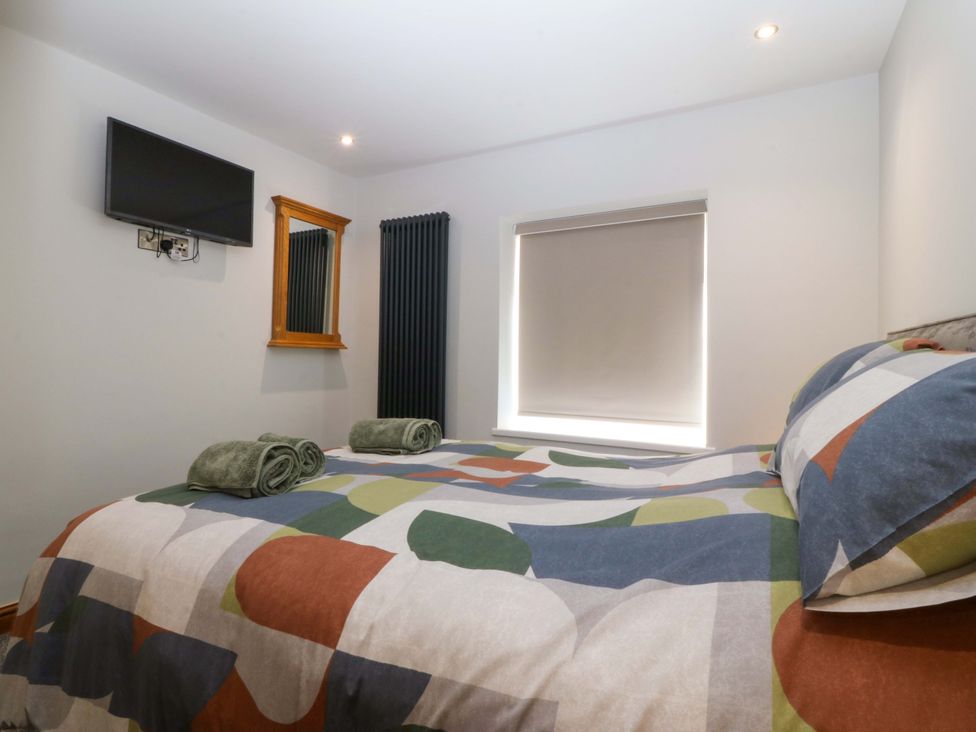 A bedroom with a bed and television at Dalar Deg in Aberdaron
