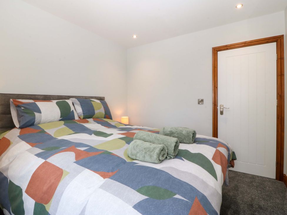 A bedroom with a bed and towels on top at Dalar Deg in Aberdaron