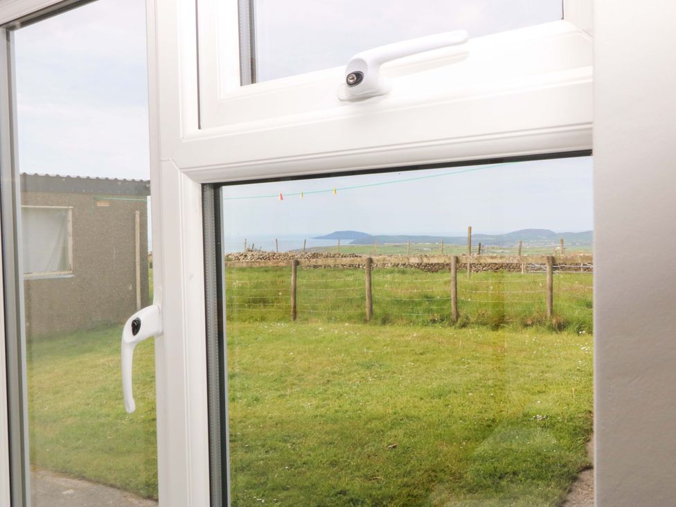 A window view showing grass and mountains at Dalar Deg in Aberdaron