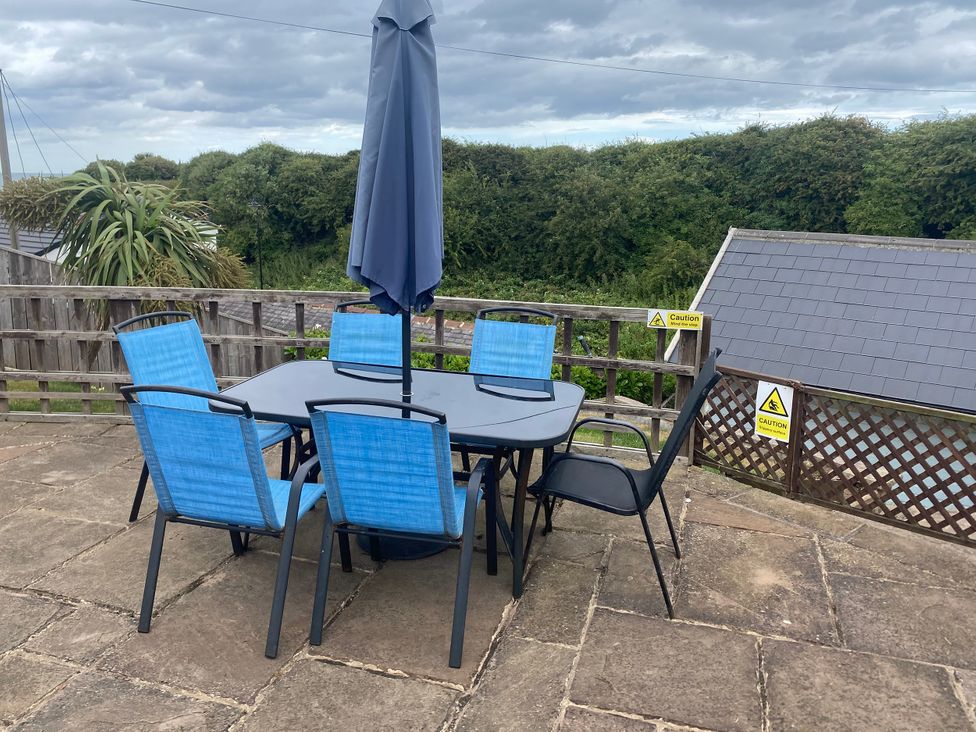An outdoor dining set with blue chairs and an umbrella at 204 Sea View House in Marske-by-the-Sea