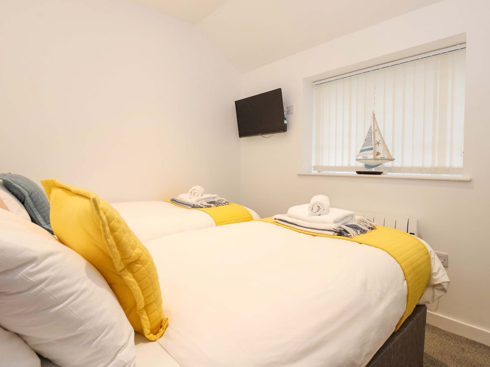 A bedroom with two beds and a television at Fishermans Loft in Mevagissey