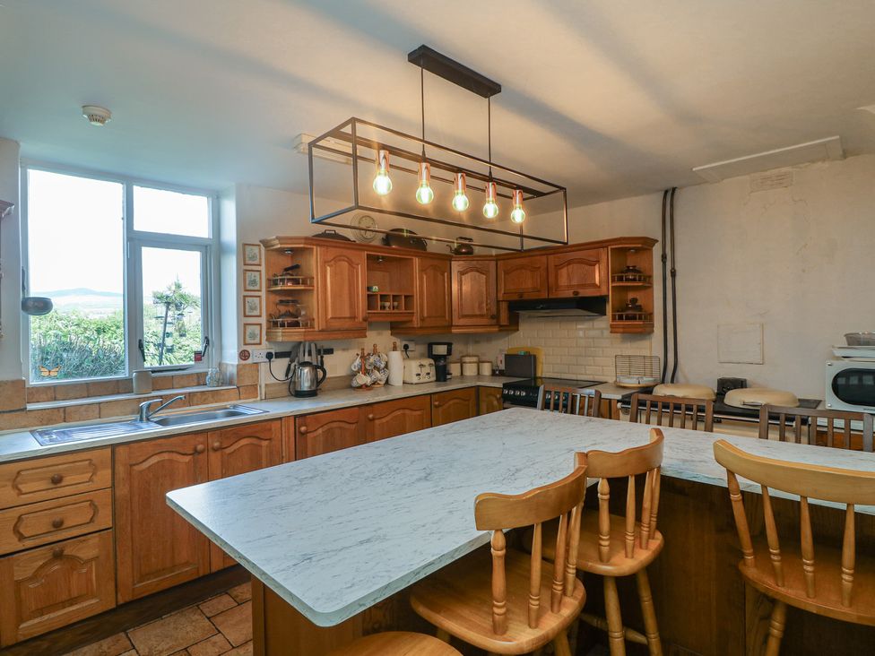 A kitchen with wooden cabinets and a marble countertop at Cairbre House in Dungarvan, County Waterford