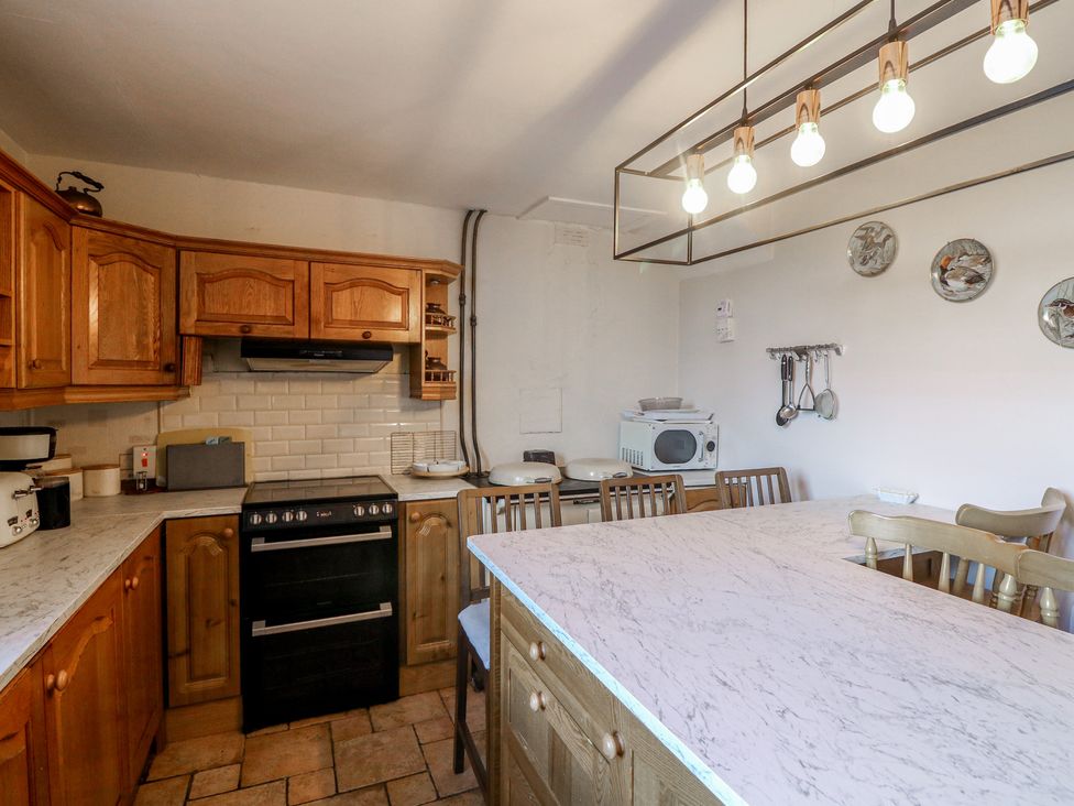 A kitchen with cabinets, stove, microwave, and table at Cairbre House, Dungarvan, County Waterford