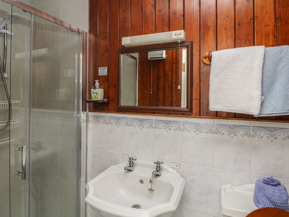A bathroom with a shower, mirror, sink and towels at Cairbre House in Dungarvan, County Waterford