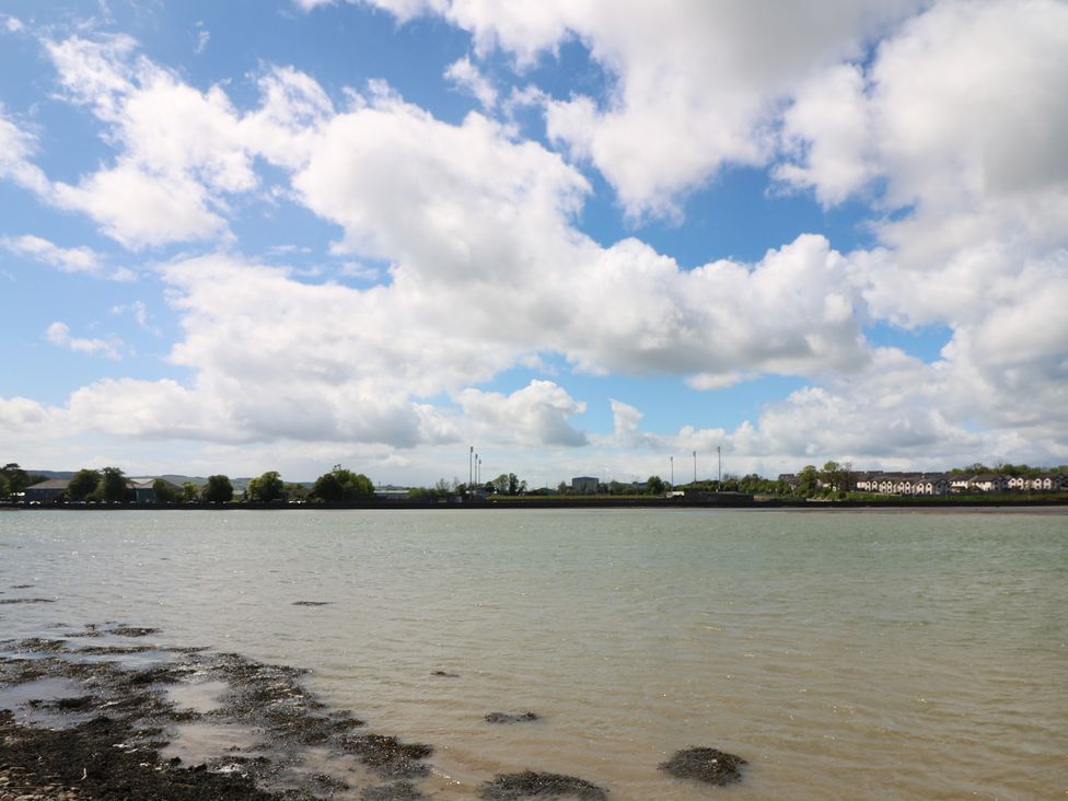 A river with buildings and trees in the background at Cairbre House, Dungarvan, County Waterford