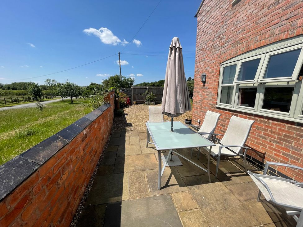 A table with chairs and a parasol at Grooms Cottage in Uppingham