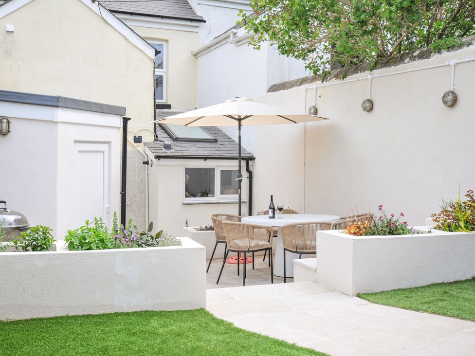 A garden with a table and chairs under an umbrella at Cecily Cottage in Westward Ho!