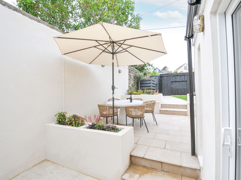 A garden with a table and chairs under an umbrella at Cecily Cottage in Westward Ho!