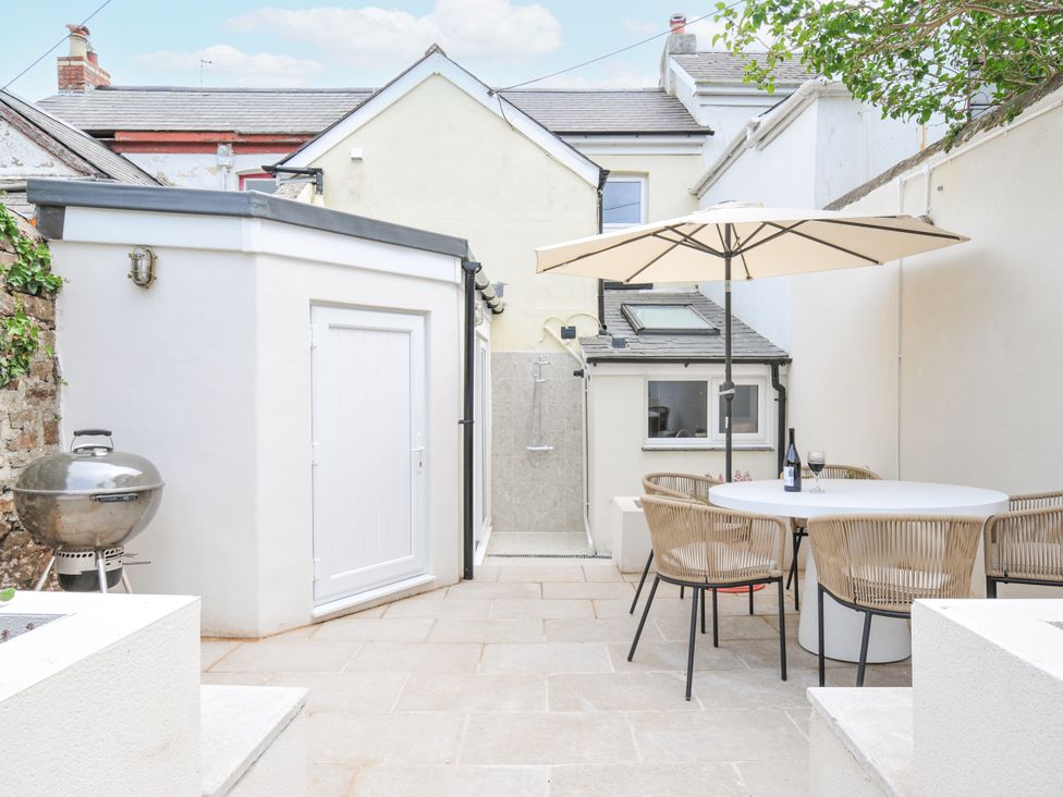 A garden with a table, chairs and an outdoor shower at Cecily Cottage in Westward Ho!