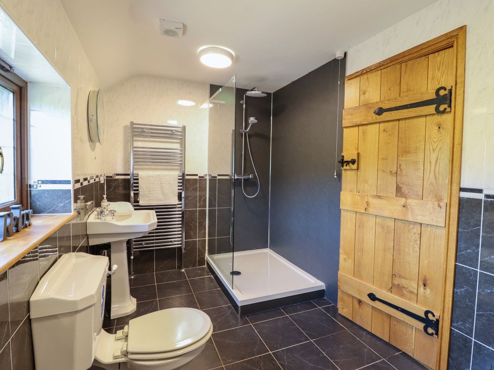 A bathroom featuring a sink, toilet, shower, and towel rail at Ty Berllan in Caersws
