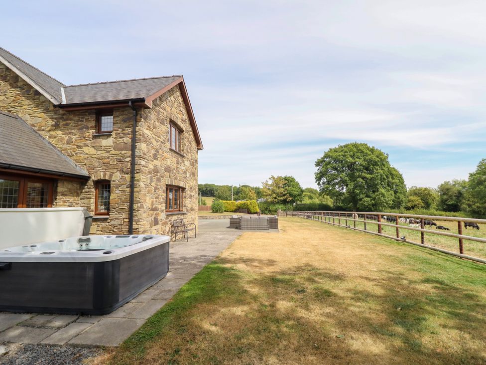 An outdoor area with a hot tub and a stone wall at Ty Berllan in Caersws
