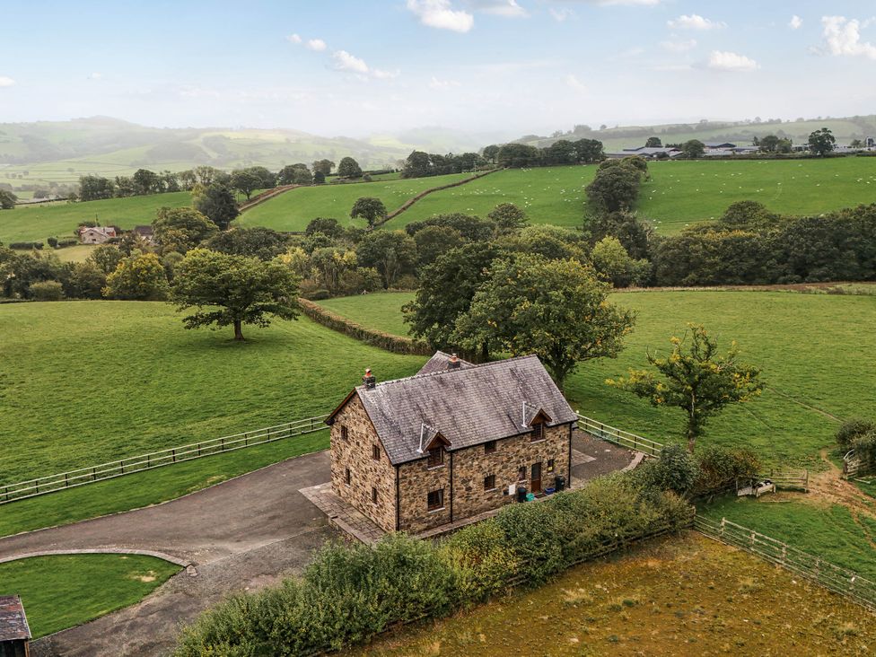 A house surrounded by fields and trees at Ty Berllan in Caersws