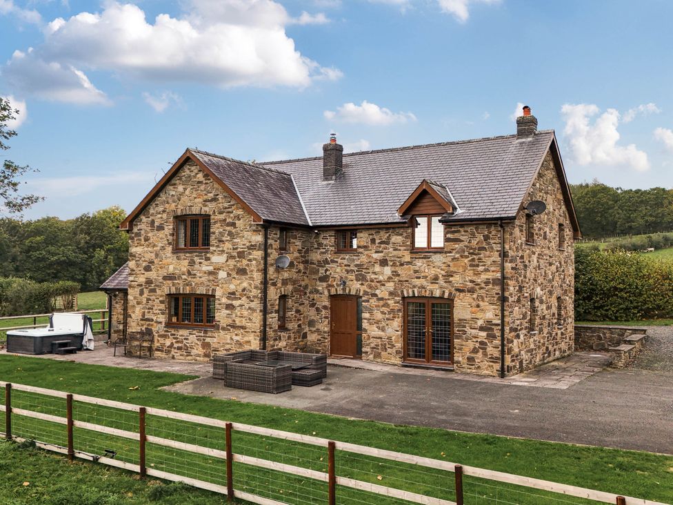 A house with stone walls and a hot tub at Ty Berllan, Caersws