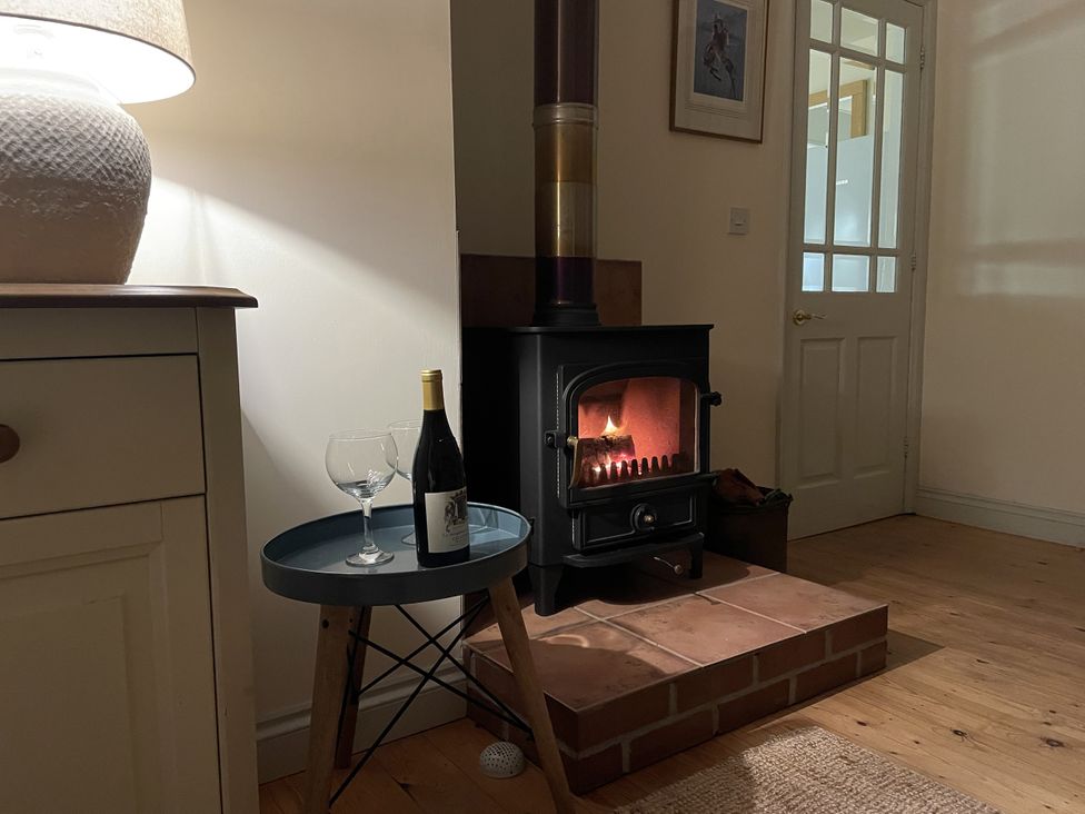 A living room with a stove, wine and glasses at Oreo's Cottage St Agnes