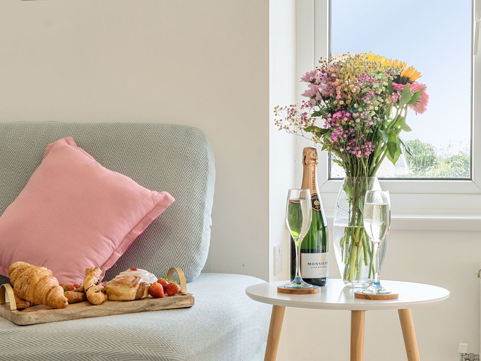 A sofa with a cushion and breakfast items at Chi An Mor in Porth