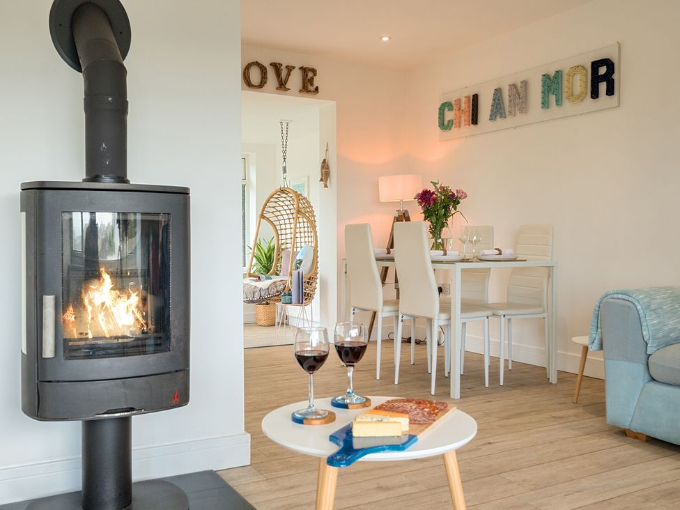 A living room with a wood stove and dining table at Chi An Mor in Porth