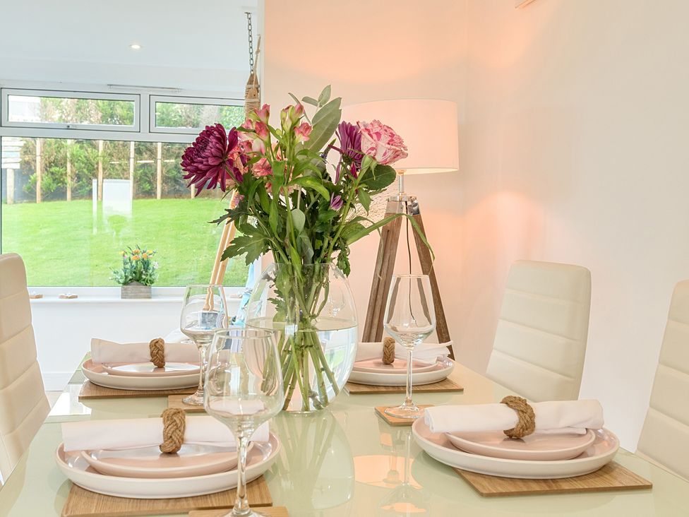 A dining room with a table set and flowers at Chi An Mor in Porth
