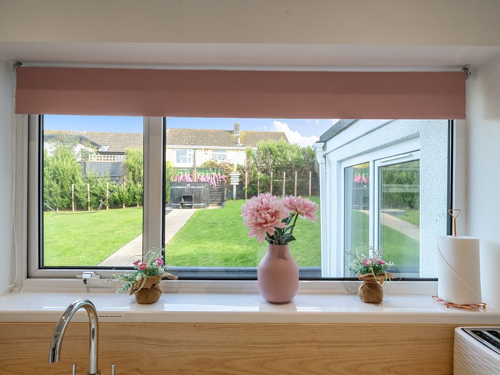 A kitchen window with a flower vase and sink at Chi An Mor in Porth