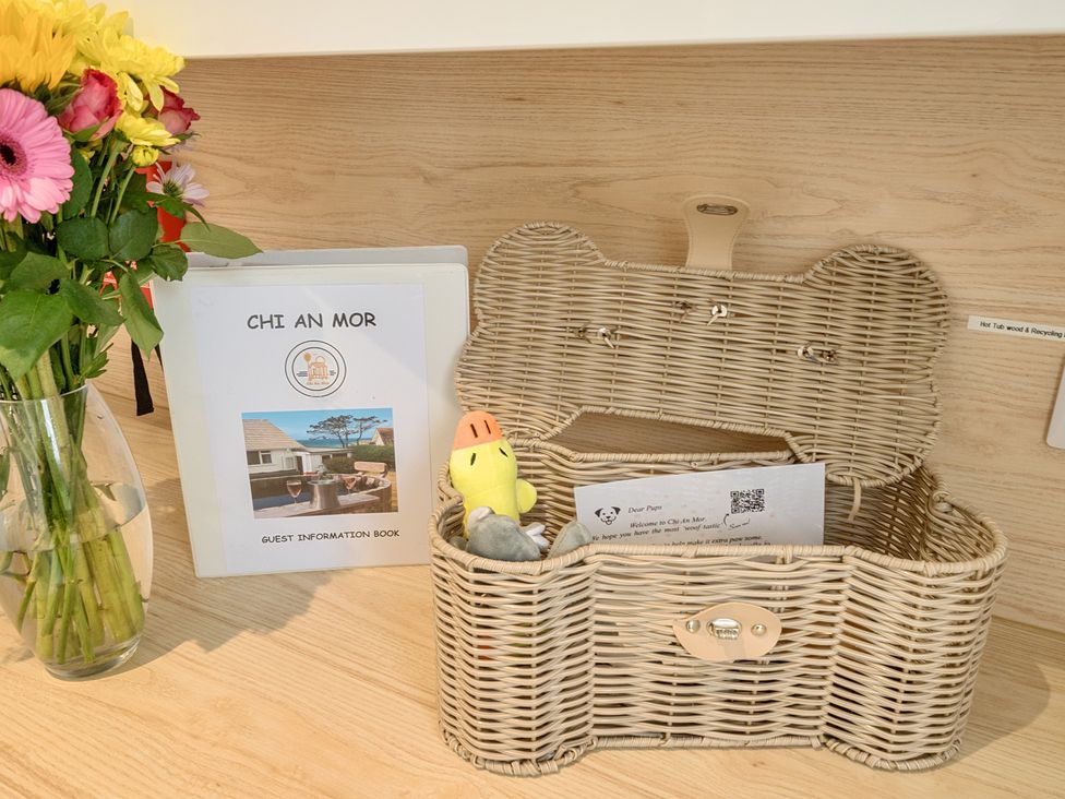 A basket with a guest information book and flowers at Chi An Mor in Porth