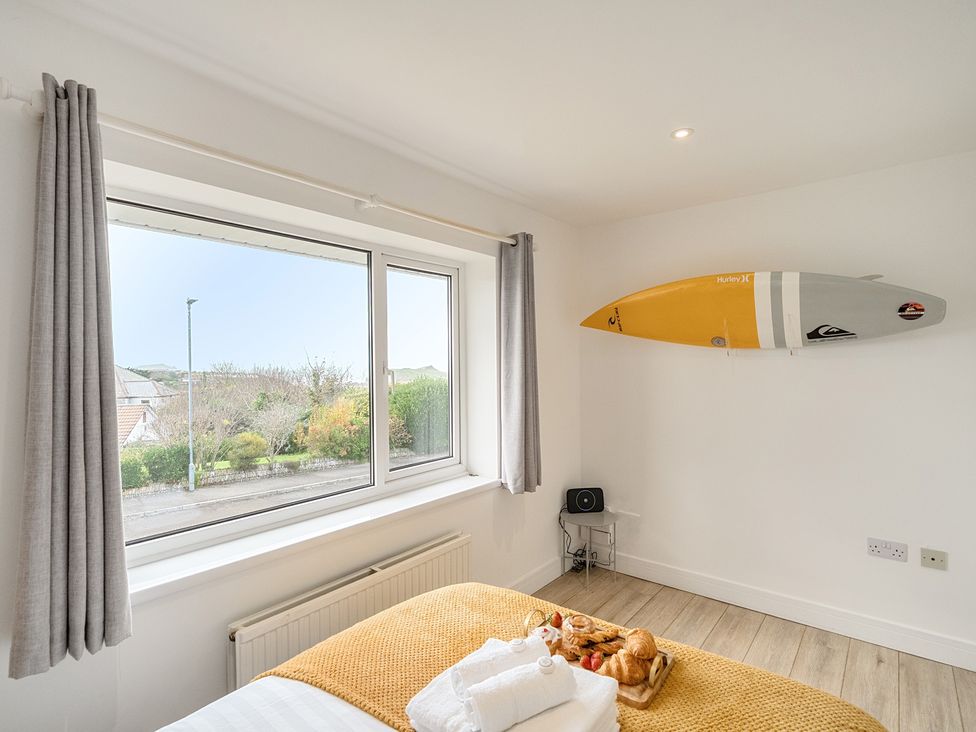A bedroom with a window and surfboard on the wall at Chi An Mor in Porth