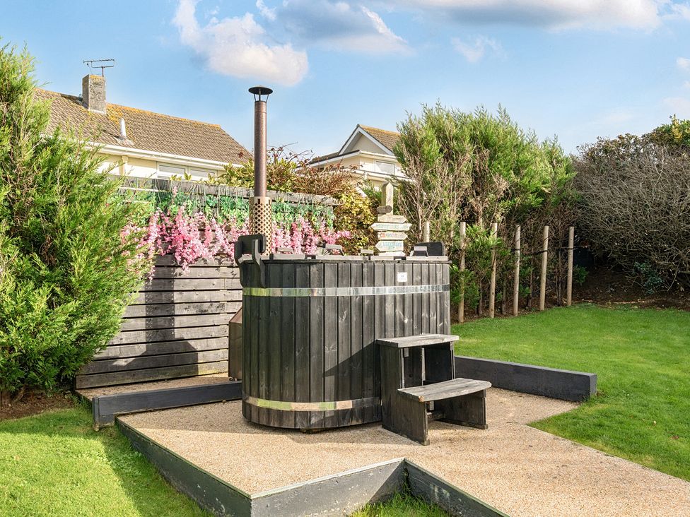A hot tub with wooden steps in the garden at Chi An Mor in Porth