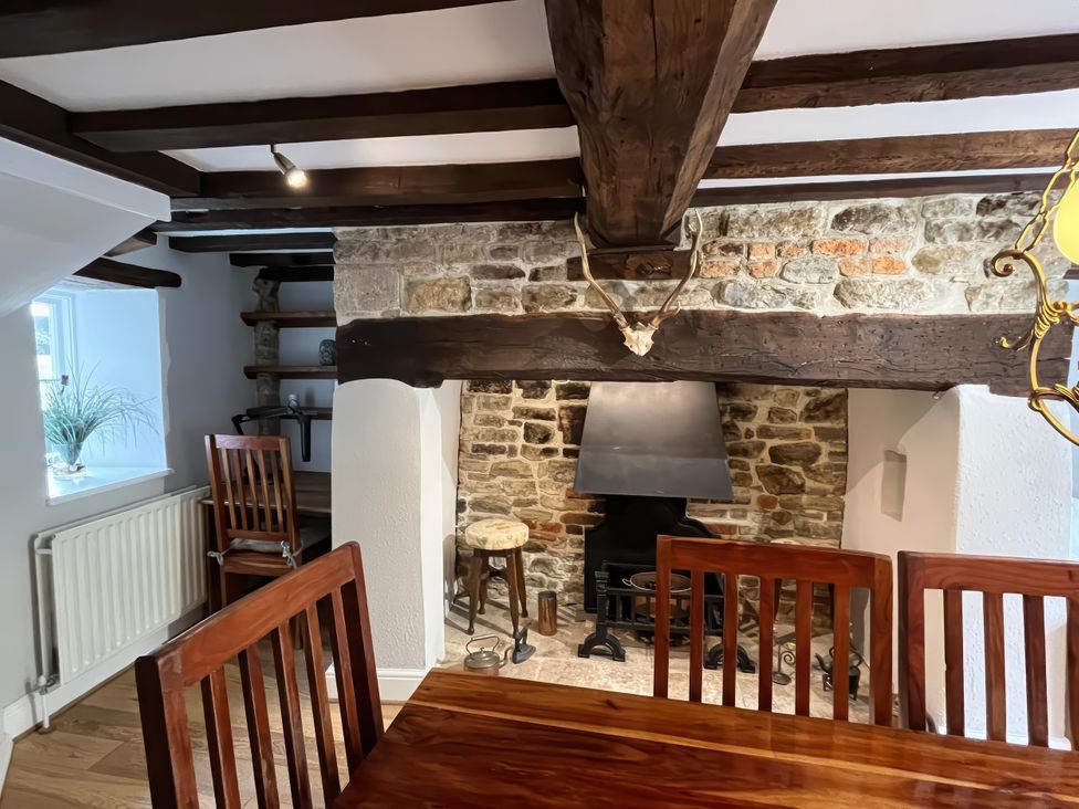 A dining room with a fireplace and wooden furniture at Ivy Cottage West Lulworth