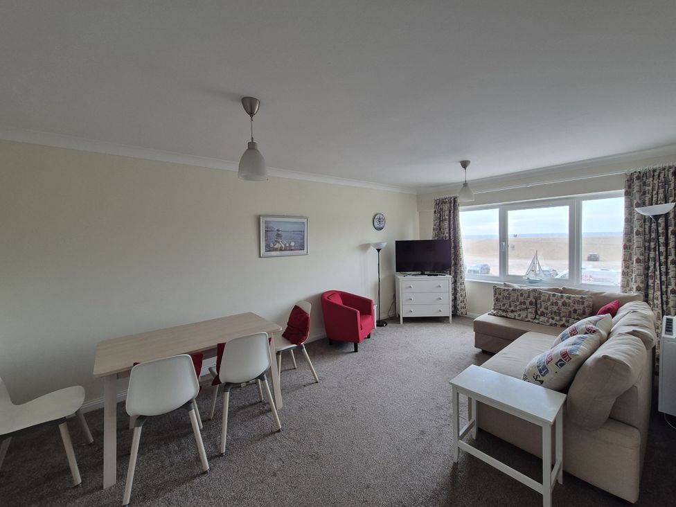 A living room with a sofa and dining area at Jurassic View West Bay