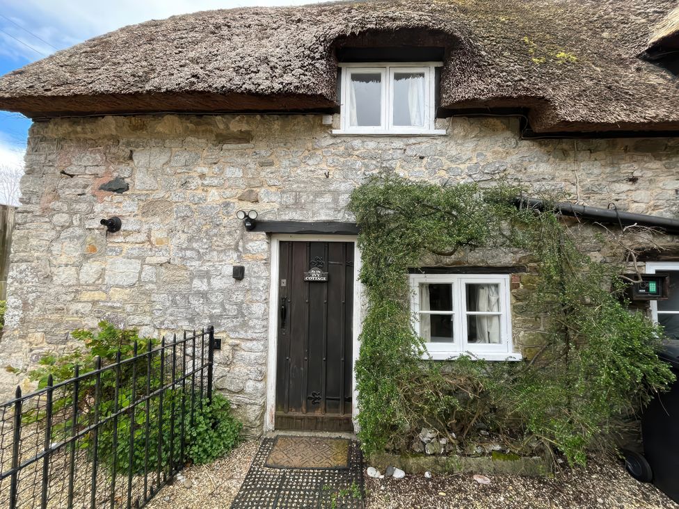 A cottage with a thatched roof and stone walls at Little Ivy in West Lulworth