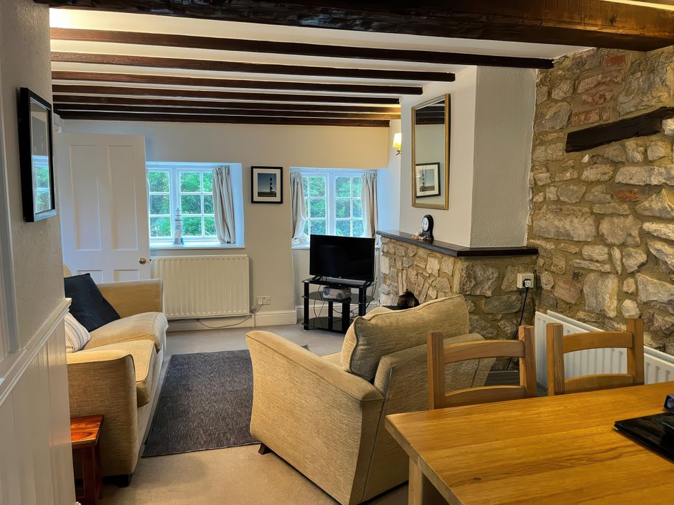 A living room with a sofa and television at Little Ivy in West Lulworth