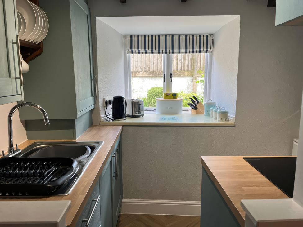 A kitchen with a sink and kitchen appliances at Little Ivy in West Lulworth