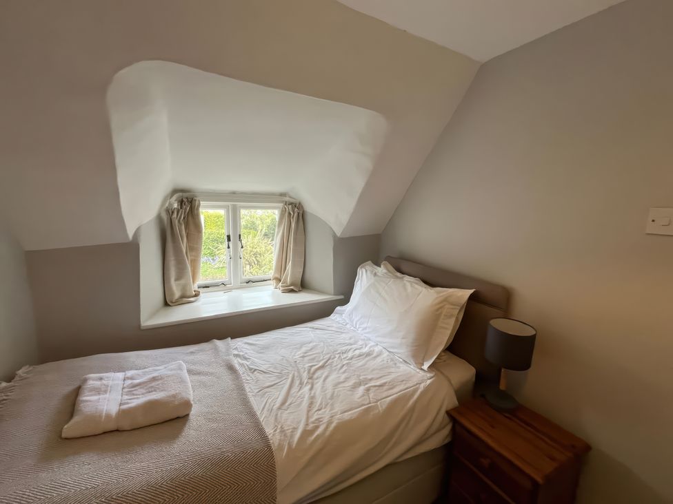 A bedroom with a bed and window at Little Ivy in West Lulworth