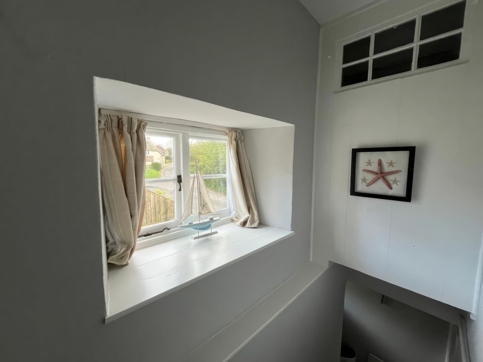 A staircase with a window and a sailboat decoration at Little Ivy in West Lulworth