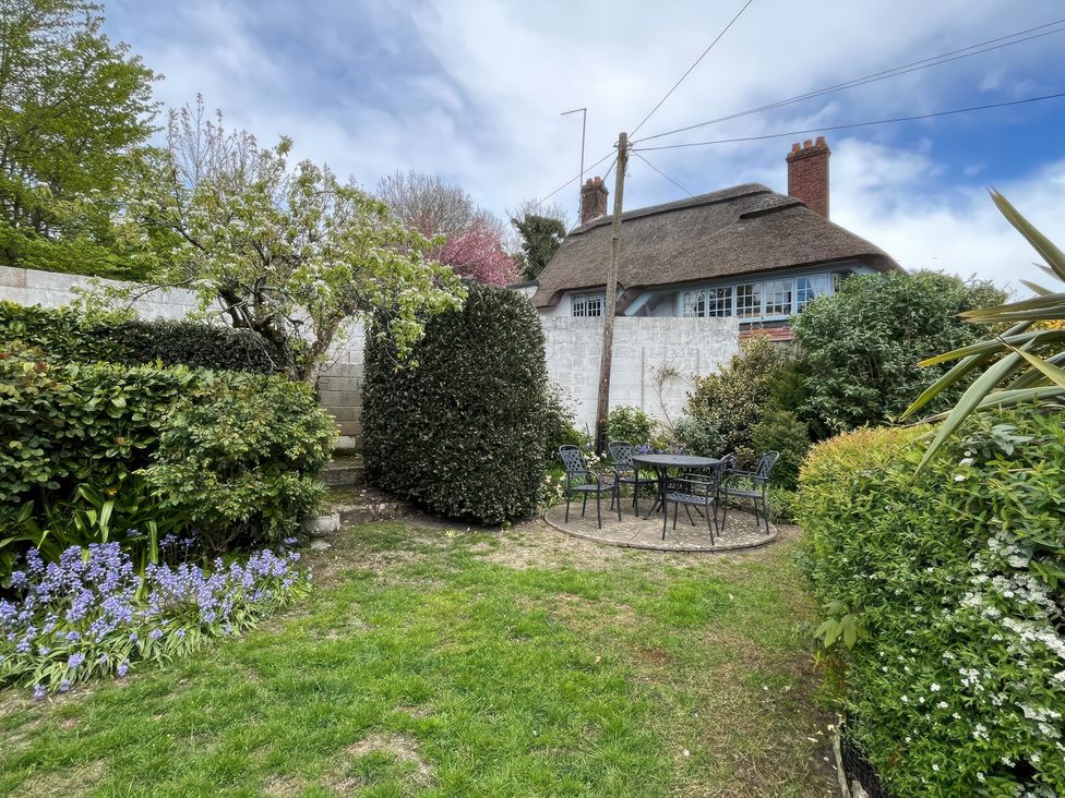 A garden with a circular table and chairs at Little Ivy in West Lulworth