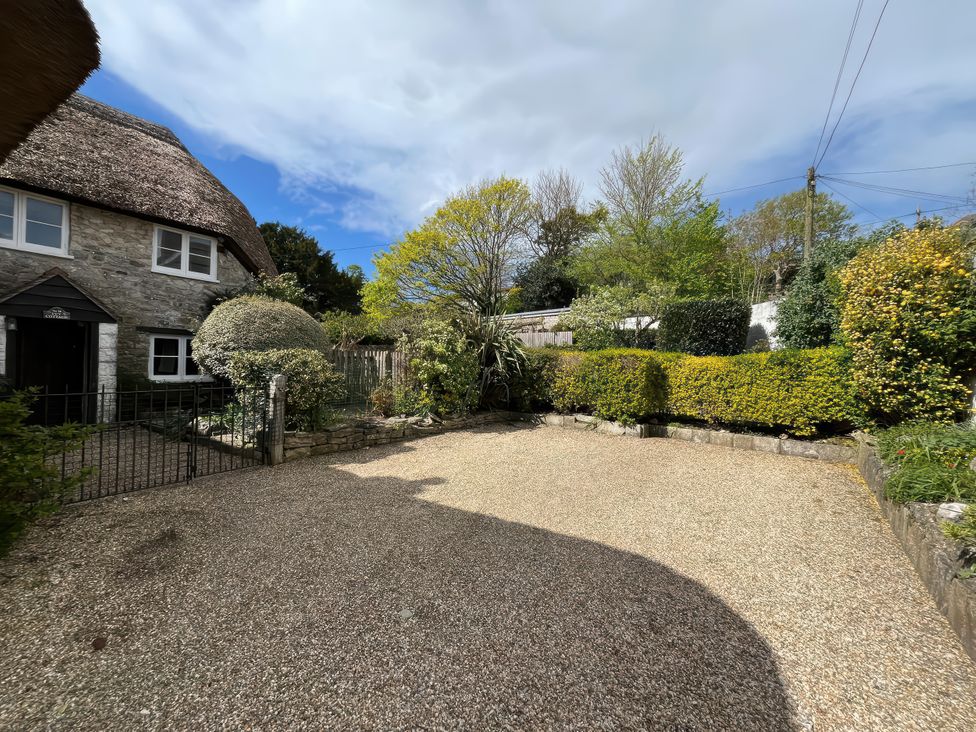 An outdoor area with a gravel driveway and a stone house at Little Ivy in West Lulworth