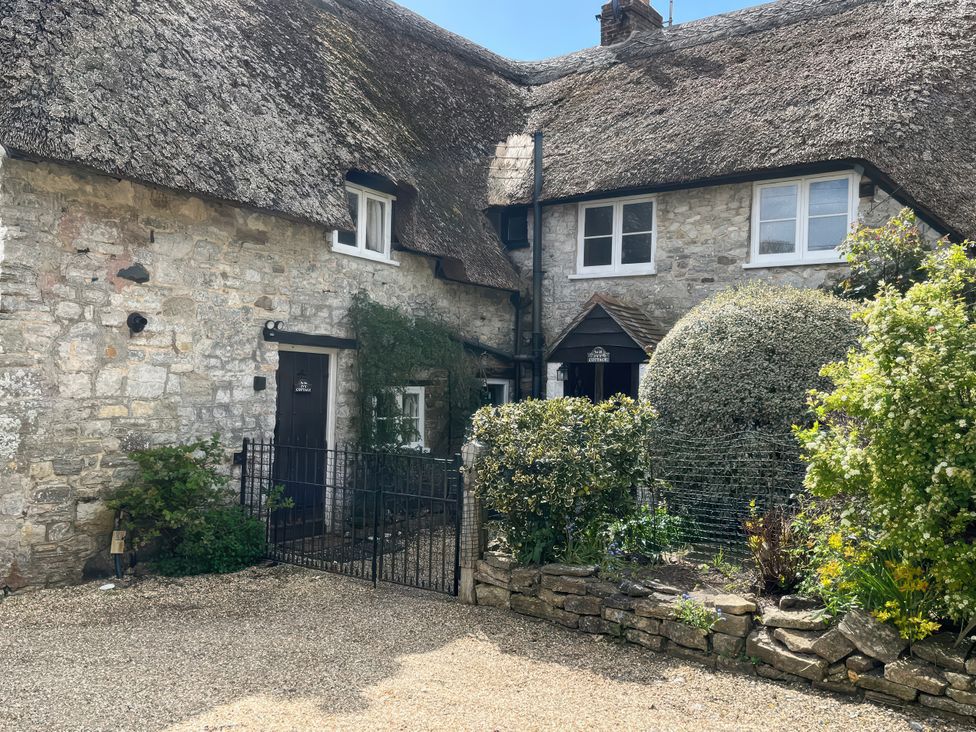 Exterior view of a cottage with stone walls and a thatched roof at Little Ivy in West Lulworth
