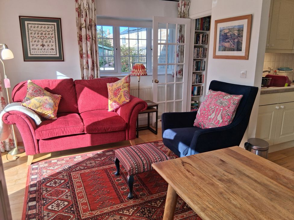 A living room with a red sofa and blue armchair at Little Retreat in Upwey