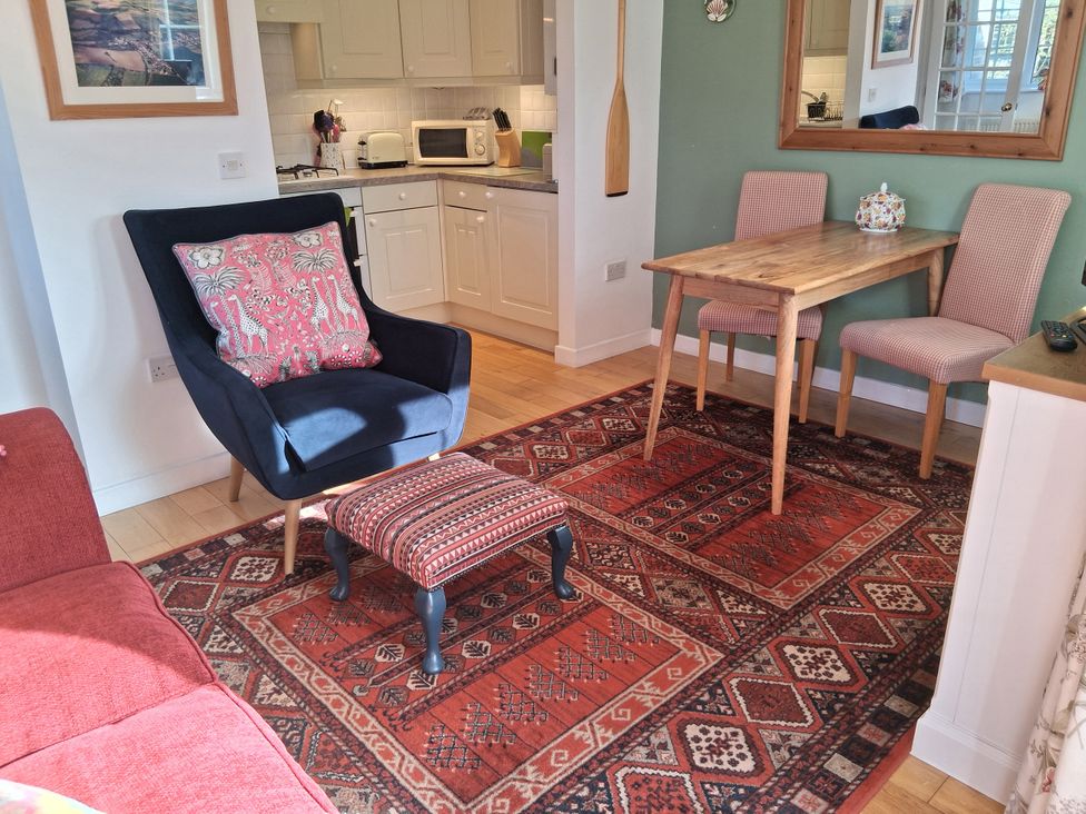 A dining room with an armchair and table at Little Retreat Upwey