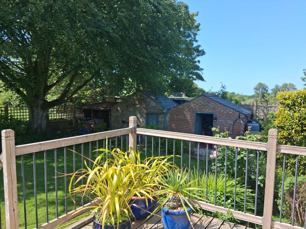 A garden with decking, plants and sheds at Little Retreat, Upwey